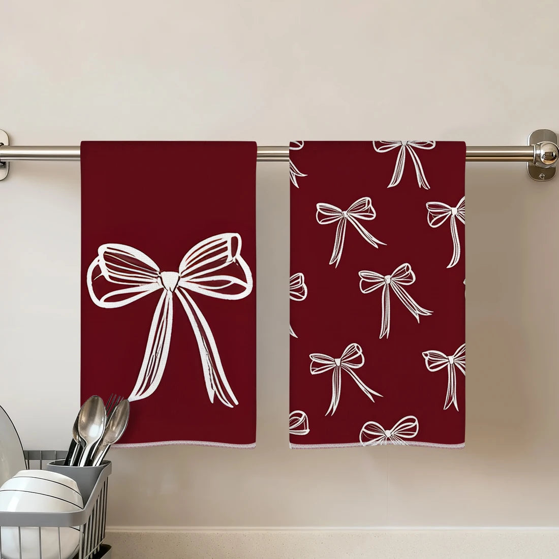 Two deep red kitchen towels with white bow patterns hanging on a metal rod.