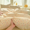 A beige duvet set with a cute dog print featuring small colorful dots, displayed on a bed.