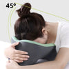 A person is using a gray memory foam U-shaped travel neck pillow for neck support, shown at a 45-degree angle.