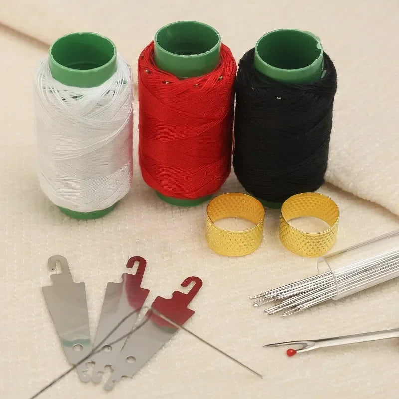 A set of stainless steel big-eye sewing needles and colored thread spools on a light fabric background.