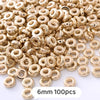 A pile of gold-colored geometric acrylic beads, 6mm size, for jewelry making.