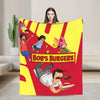 A colorful throw blanket featuring cartoon characters and text promoting Bob's Burgers.
