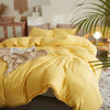 A bright yellow duvet cover set with pom-pom decoration displayed on a bed.
