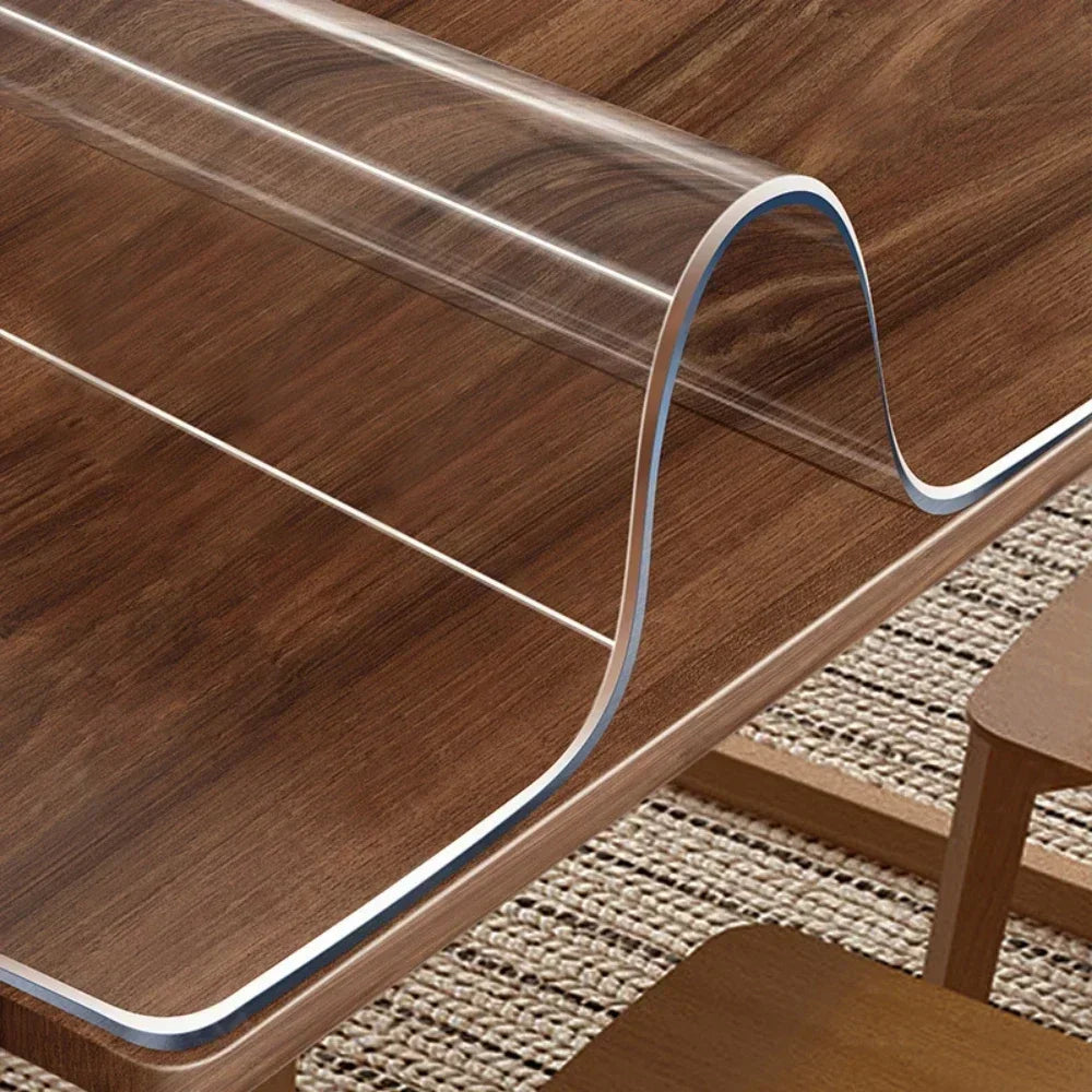 A clear PVC table protector mat is shown draped over a wooden table surface.