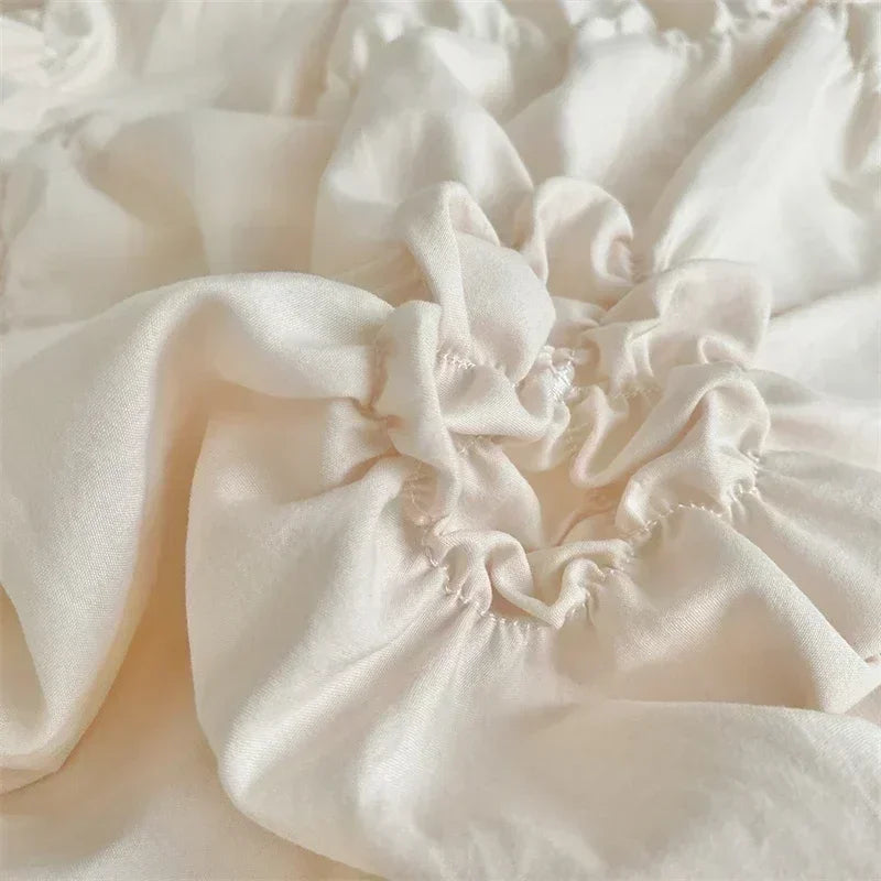 Close-up of a cream colored pinch pleat duvet cover fabric showing soft folds and texture.