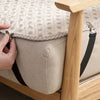 A hand is using clips to attach a sheet to an adjustable bed mattress cover.