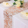 A white table setting featuring a rose gold sequin glitter table runner, white plates with gold-wrapped napkins, and white fl