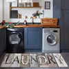A modern laundry room featuring a wooden countertop, built-in cabinets, and two front-loading washing machines.