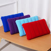 A collection of colorful inflatable travel pillows in blue, purple, and red resting on a wooden surface.