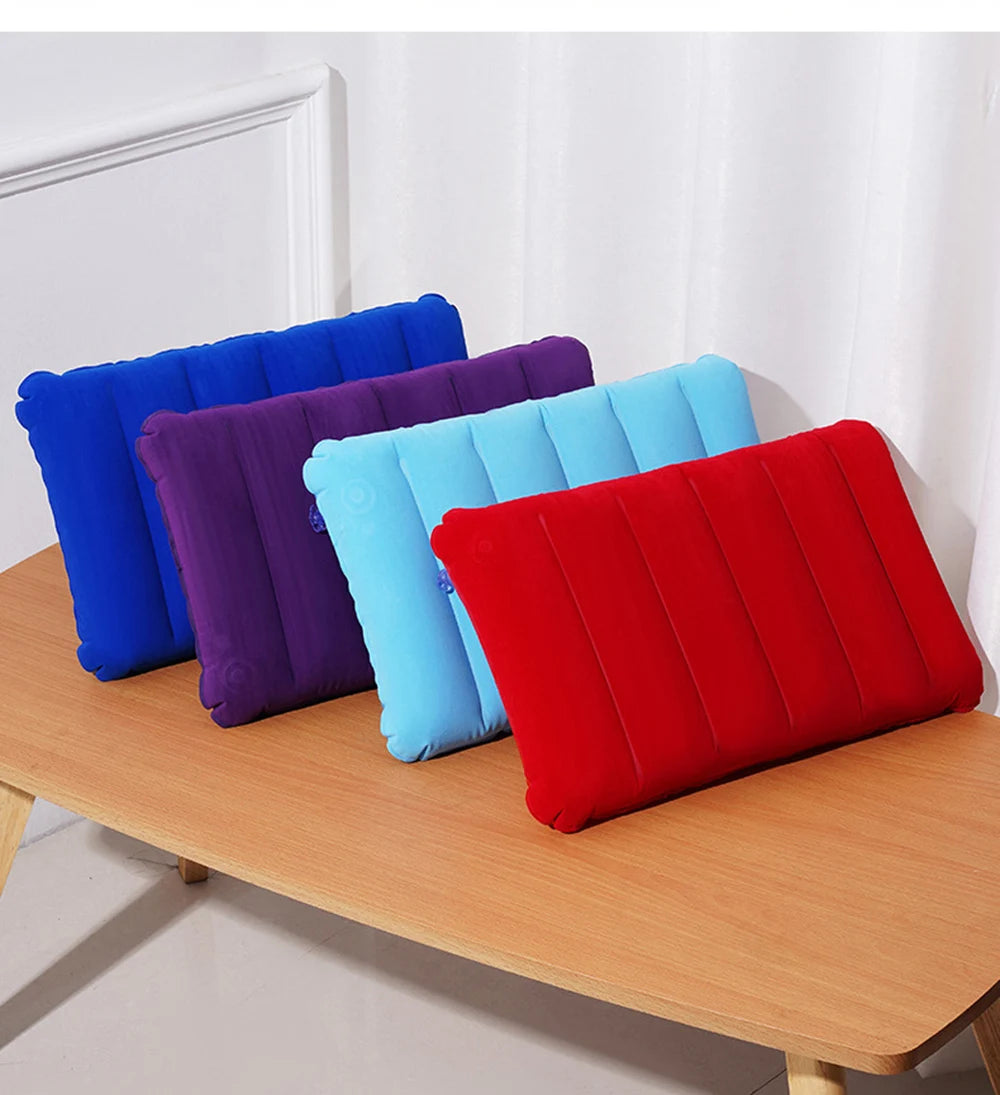 A collection of colorful inflatable travel pillows in blue, purple, and red resting on a wooden surface.