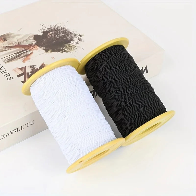 A spool of black and white elastic sewing thread is displayed in a wooden holder.