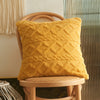 A textured yellow geometric plaid cushion cover resting on a light wooden chair.