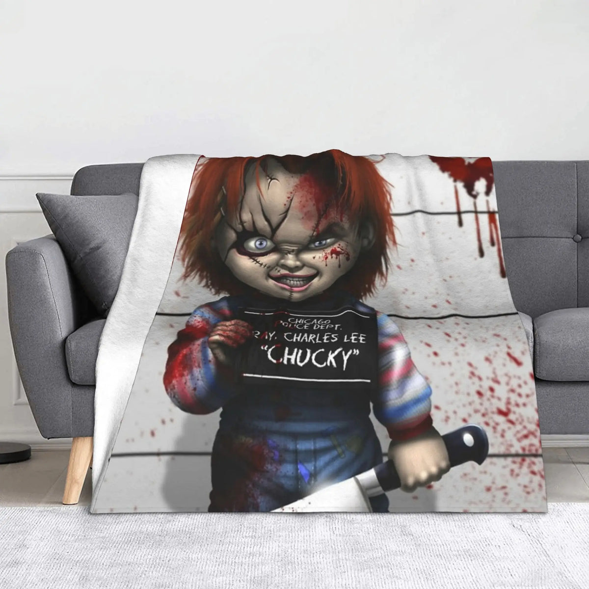 A plush blanket featuring a graphic of Chucky the doll with blood splatter and a distressed expression.