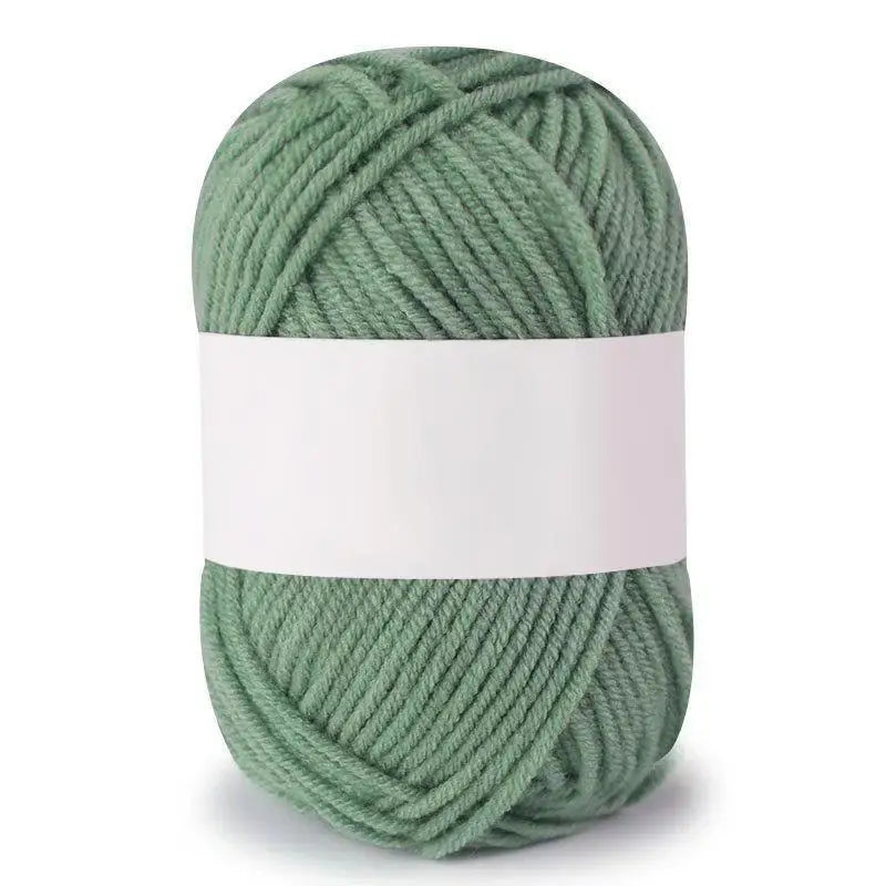 A ball of soft milk cotton knitting yarn in a muted sage green color.