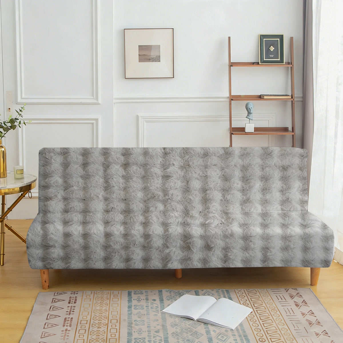 A gray velvet non-slip armless sofa cover displayed on a wooden floor with an oriental rug.