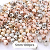 A pile of small geometric acrylic beads in rose gold and silver colors for jewelry making