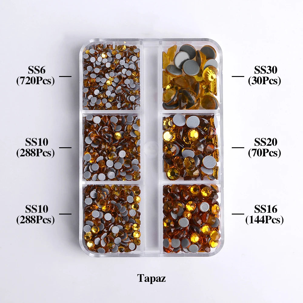 A transparent plastic tray holds various sizes of gold and bronze glass rhinestones categorized by SS6, SS10, SS10, SS30, SS2