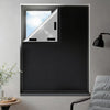 A close-up view of a window with black blackout curtains featuring adhesive strips, showing the light filtering through.