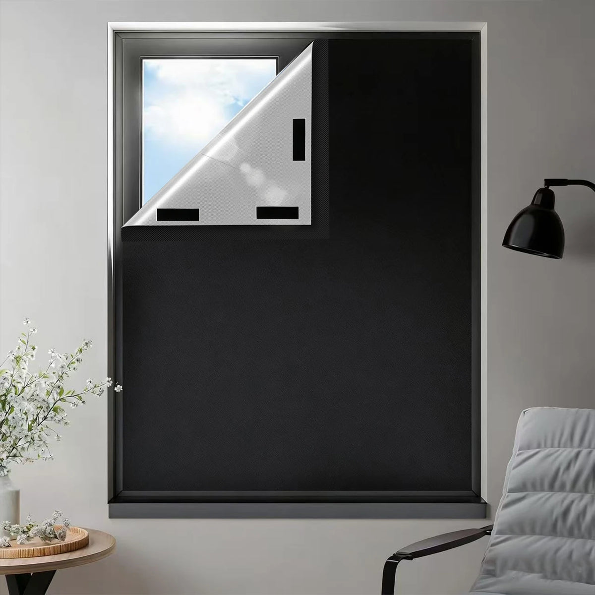 A close-up view of a window with black blackout curtains featuring adhesive strips, showing the light filtering through.