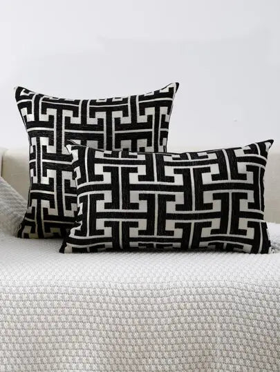 Black and white geometric patterned throw pillows resting on a white textured surface.