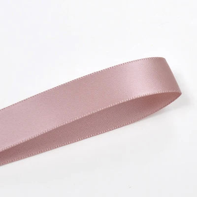 A roll of pink double-sided satin craft ribbon shown in profile.