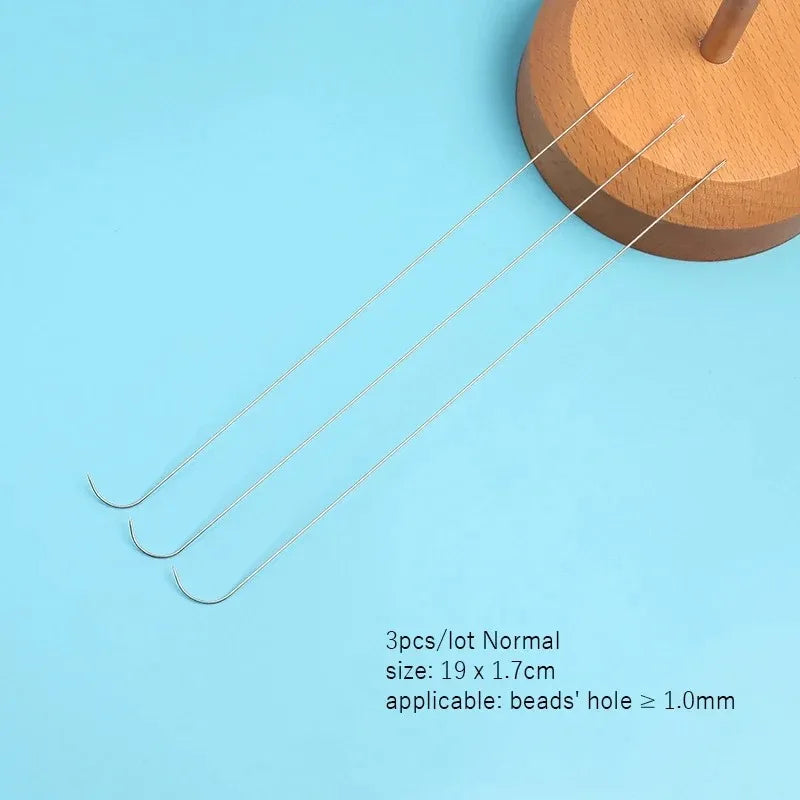 A set of three stainless steel beading needles with a wooden holder are displayed on a light blue background.