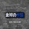 A black embroidered badge with Japanese text 全村の希望 and a size specification of 9x2.5cm
