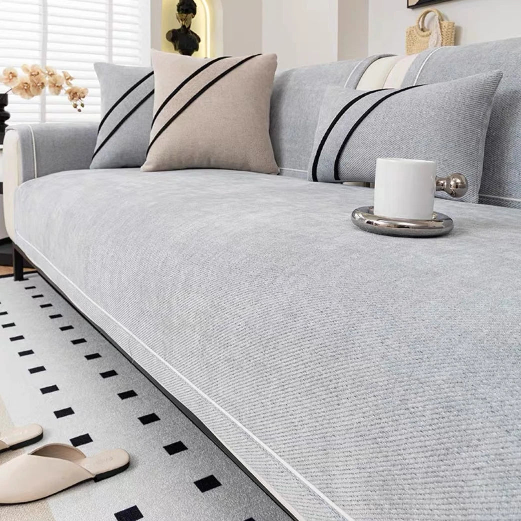 A light gray chenille sofa protector cover with black stripes and a white candle on the surface.