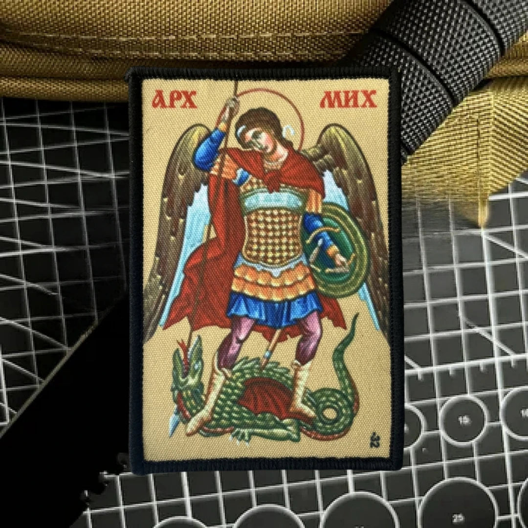 An embroidered patch depicting the Archangel Michael with wings, a sword, and a serpent, featuring red, gold, and blue colors