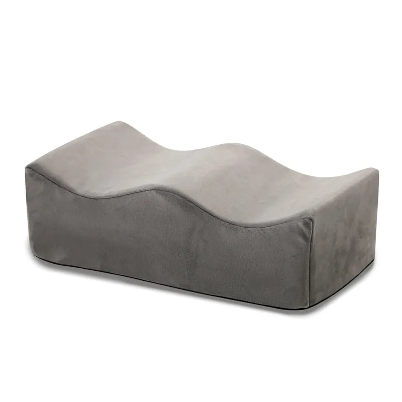A gray ergonomic memory foam leg support pillow shown from the side.
