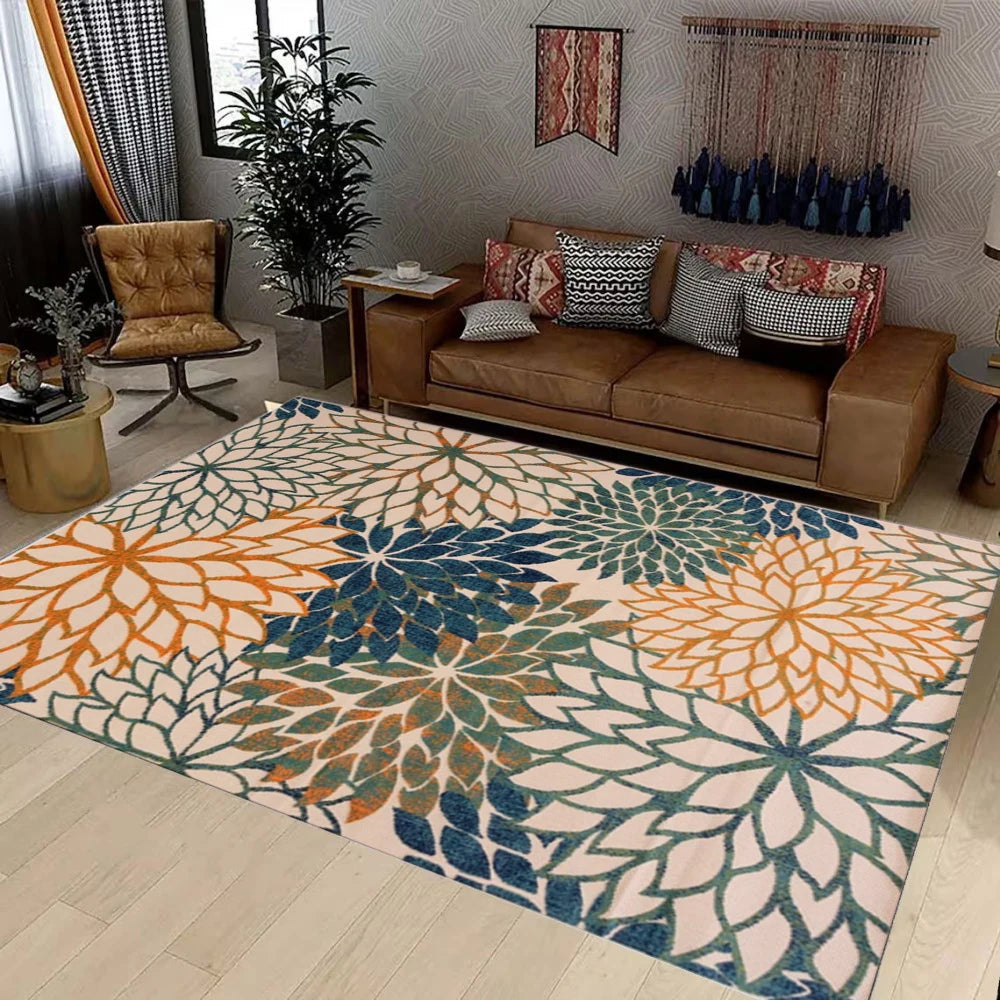 A large outdoor area rug featuring a tropical botanical pattern in shades of orange, teal, and blue on a light floor.