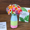 A colorful bouquet of felt flowers in various shades of pink, orange, yellow, and green displayed in a glass vase.