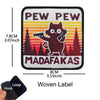 A black woven label embroidered with the text PEW PEW and MADAFAKAS featuring a cat silhouette.