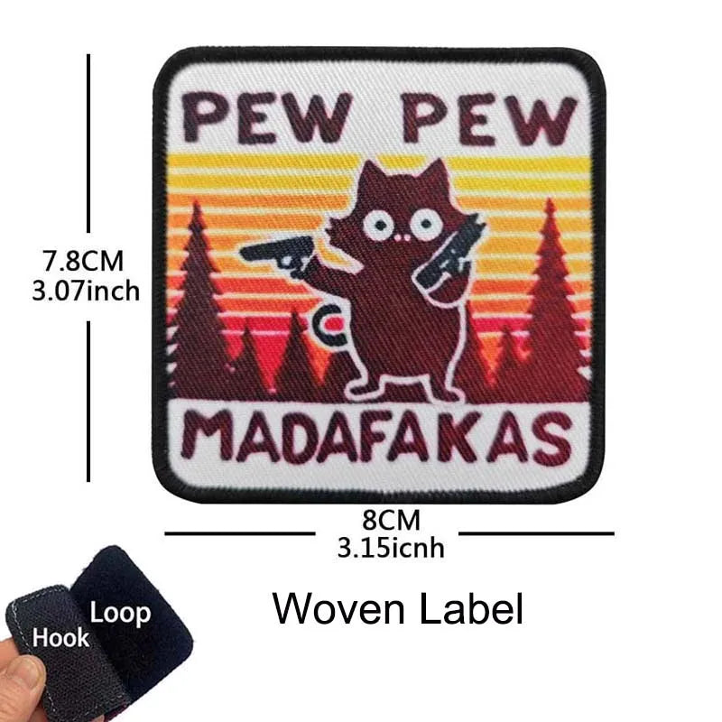 A black woven label embroidered with the text PEW PEW and MADAFAKAS featuring a cat silhouette.