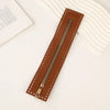 A brown PU leather zipper frame with studs is shown on a white surface.