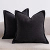 A black textured boucle throw pillow resting on a light-colored sofa.