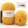 A close-up of a ball of bright yellow fuzzy yarn labeled as Plant Made Coral Velvet Yarn for crafting.