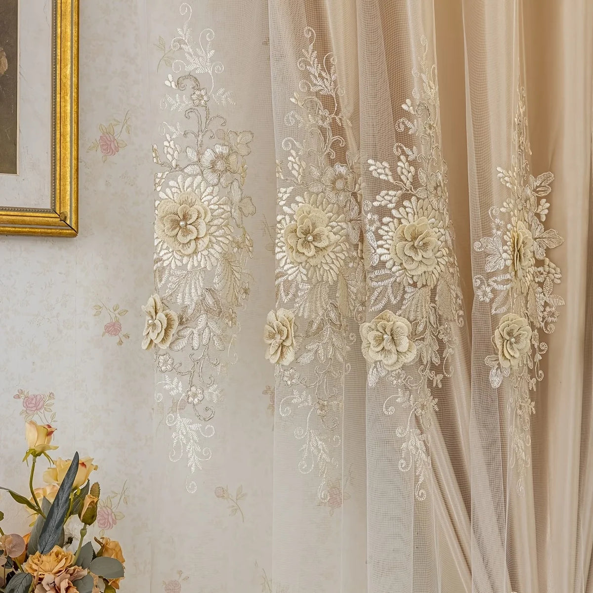 A close-up of a sheer, cream-colored curtain with delicate floral lace detailing and gathered fabric.