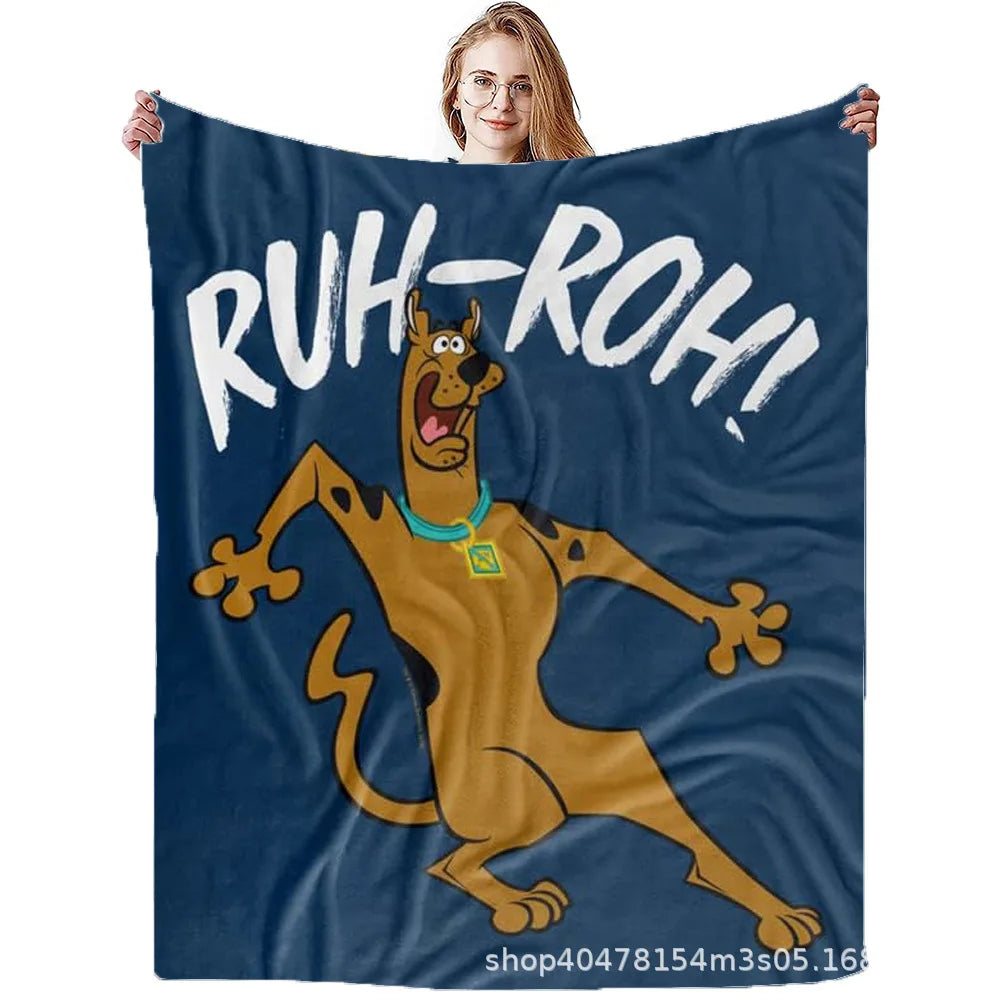 A person holds up a dark blue flannel throw blanket featuring a graphic of a dog shouting Ruh-Roh!