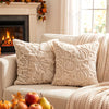 A collection of cream-colored fuzzy maple leaf throw pillows resting on a light sofa next to a fireplace.