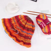 A close-up of a gradient dyed wool yarn in shades of orange, red, and yellow, displayed next to knitting needles.