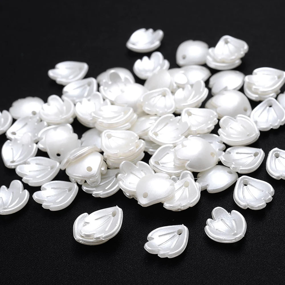 A pile of small, white imitation pearl flower spacer beads for DIY jewelry.