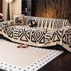 A vintage bohemian knit sofa protector featuring black and cream geometric patterns on a beige sofa.