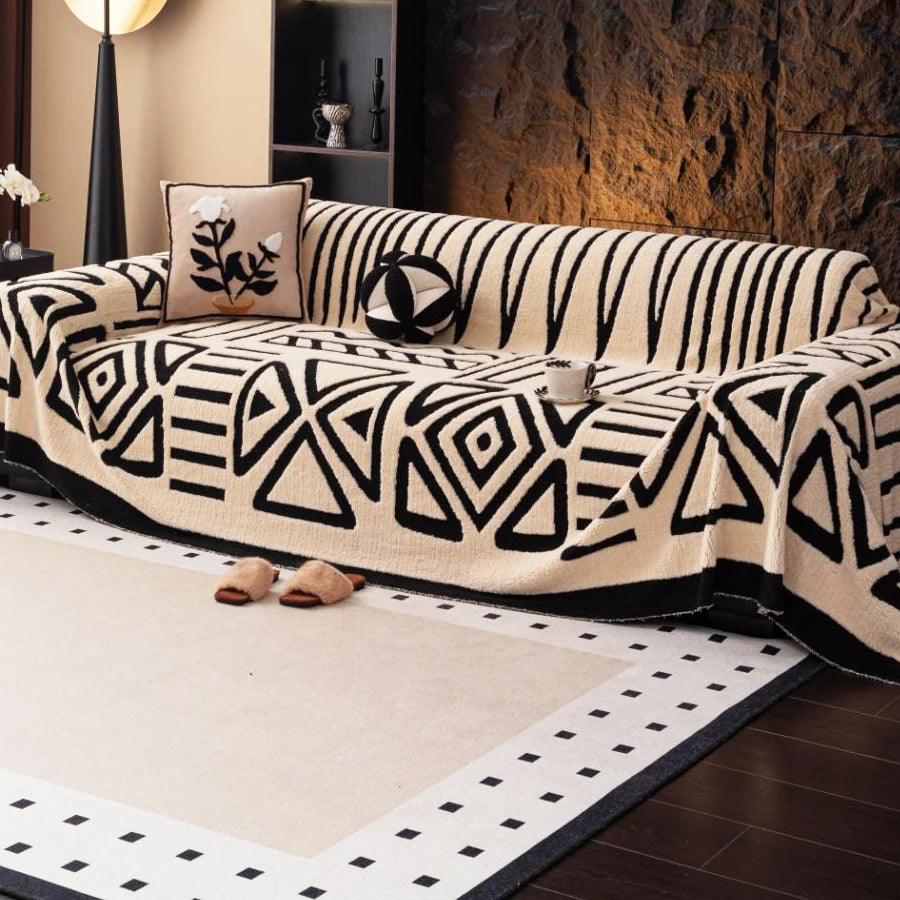 A vintage bohemian knit sofa protector featuring black and cream geometric patterns on a beige sofa.
