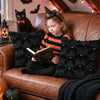 A young girl with a witch hat sits on a brown leather couch reading a book surrounded by black bat-themed cushions and Hallow