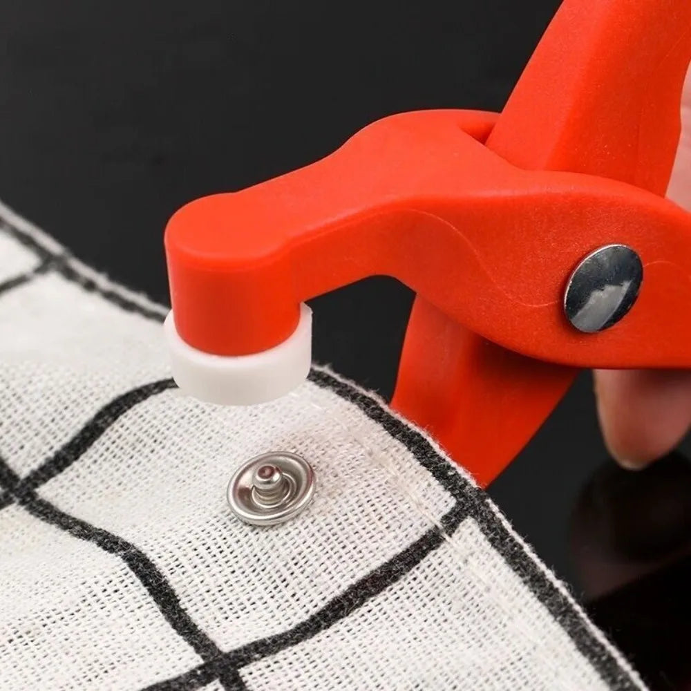 A close-up of an orange crimping pliers with a crochet hook gripping a white fabric.