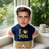 A young man is lying on a white face pillow with a navy blue shirt embroidered with the text I love you and a gold heart.