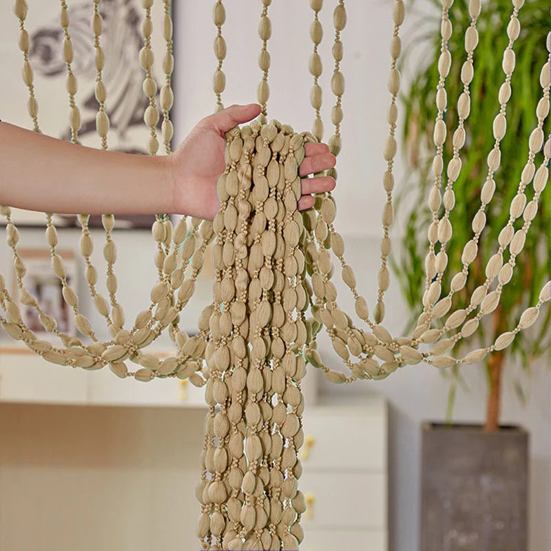 A hand is adjusting a decorative fabric door curtain with tassel trim, featuring beige and cream tones.