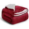 A deep red sherpa fleece blanket with a white fluffy trim, rolled up and displayed on a white background.