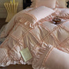 A pink ruffled duvet cover set with quilted detailing and gathered fabric is displayed on a bed.